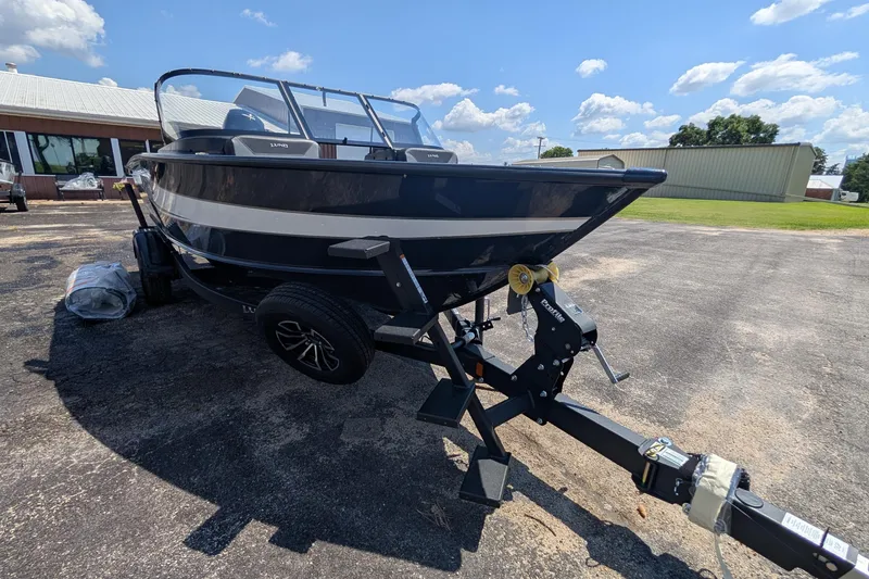 Slide: The Image of 2026 Lund 1875 Crossover XS boat on trailer, parked outdoors under a clear sky. - 15