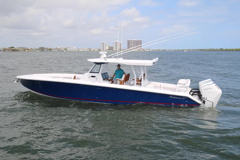 Slide: The Image of 2026 Bahama 41 GT boat cruising on open water with city skyline in background. - 23