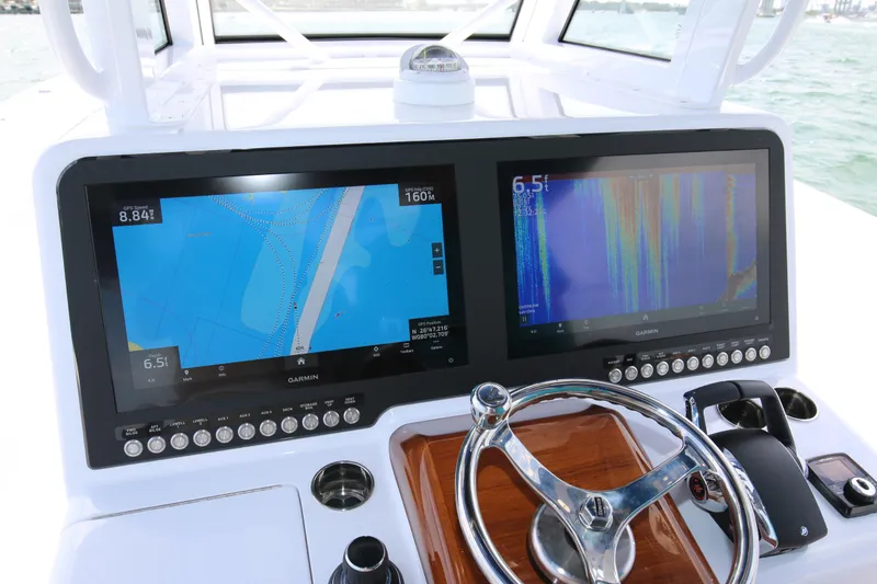 Slide: The Image of 2026 Bahama 41 GT boat dashboard with dual Garmin navigation screens and steering wheel. - 73