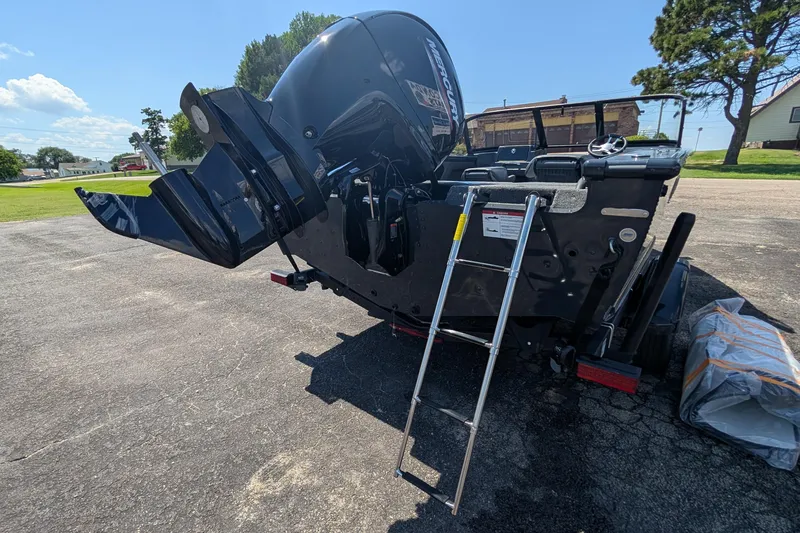 Slide: The Image of 2026 Lund 1875 Crossover XS boat with ladder and outboard motor on pavement. - 6