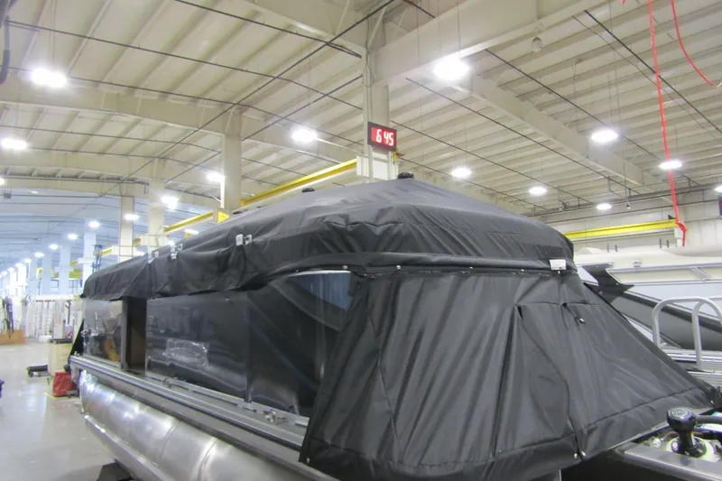 Slide: The Image of 2026 Avalon VENTURE CRUISE pontoon boat with black cover in a factory setting. - 8