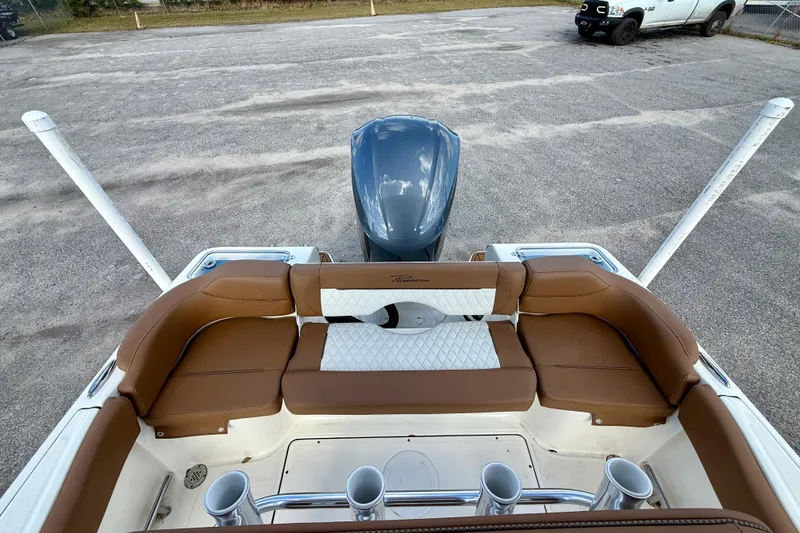 Slide: The Image of 2024 Pioneer 222 Islander boat with brown seating and motor, parked on pavement. - 6