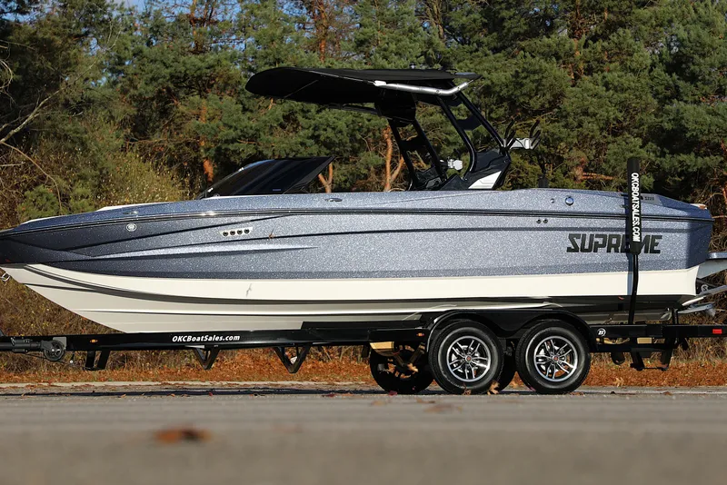 Slide: The Image of 2026 Supreme S220 boat on trailer, parked outdoors with trees in background. - 31