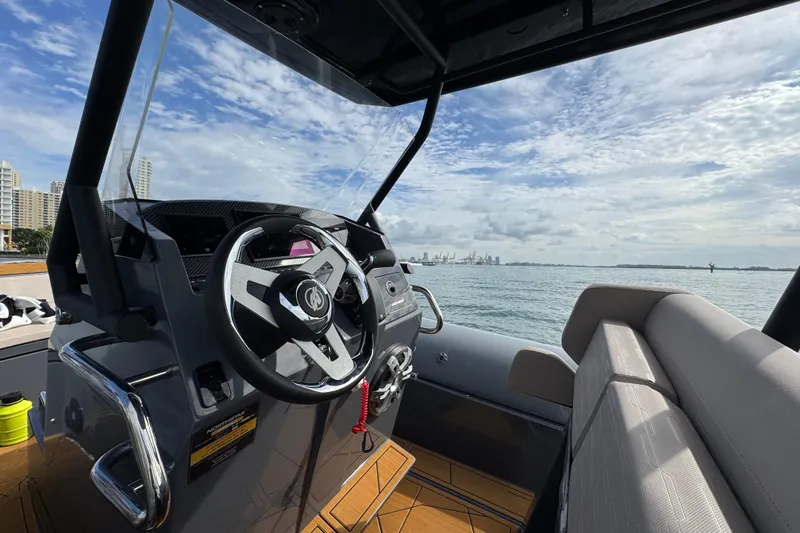 Slide: The Image of 2026 Northstar Orion 8 boat interior with steering wheel, overlooking ocean and skyline. - 23