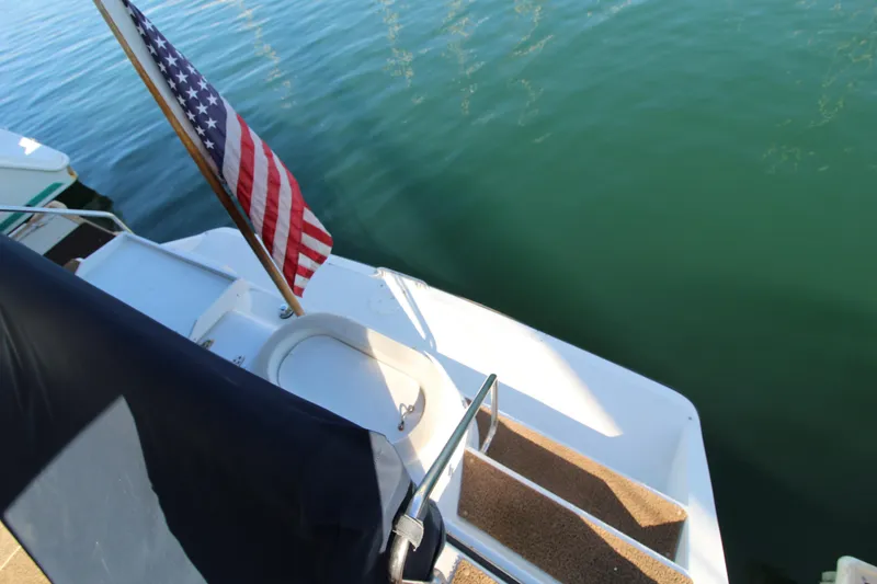 Slide: The Image of 1990 Carver 3467 Santego boat with American flag on calm water. - 19