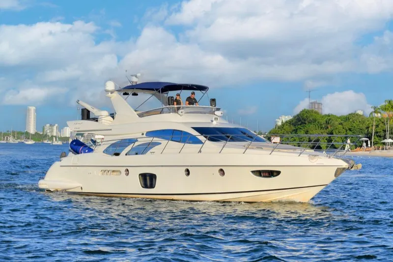 The Image of 2010 Azimut 62 Evolution yacht cruising on a sunny day near a city skyline. - 1