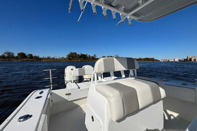 Slide: The Image of 2018 Cape Horn 24 XS boat interior with seating, on a calm water body under clear blue sky. - 16