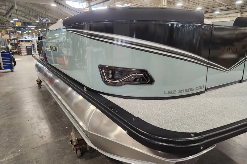 Slide: The Image of 2026 Avalon LSZ Cruise Rear Bench pontoon boat in a factory setting. - 13
