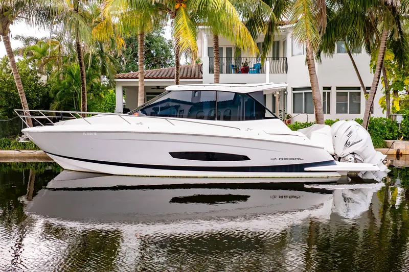 The Image of 2022 Regal 36 XO boat docked by a tropical waterfront home. - 0