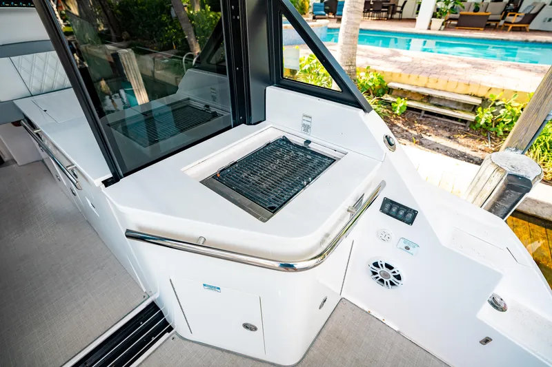 Slide: The Image of 2022 Regal 36 XO boat with outdoor grill and sleek design by a poolside. - 12