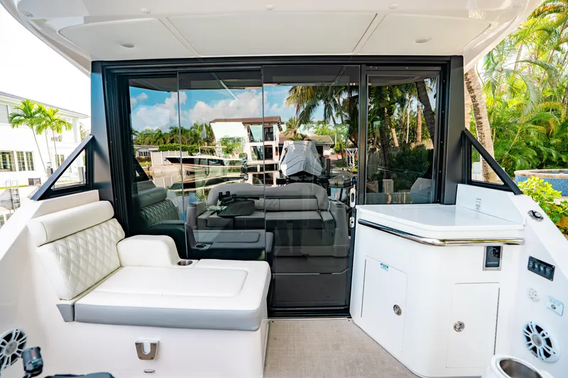 Slide: The Image of 2022 Regal 36 XO yacht interior with seating and glass doors, surrounded by tropical scenery. - 14