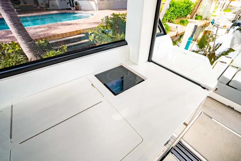 Slide: The Image of 2022 Regal 36 XO yacht interior with sleek countertop and induction cooktop near poolside. - 23