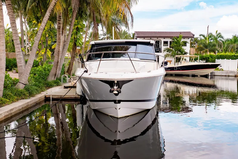 Slide: The Image of 2022 Regal 36 XO yacht docked by palm trees in a serene waterfront setting. - 5
