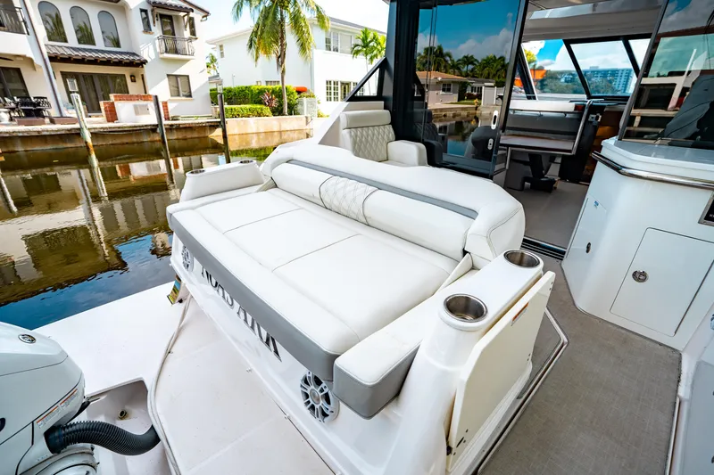 Slide: The Image of 2022 Regal 36 XO yacht with luxurious seating, docked near waterfront homes. - 9