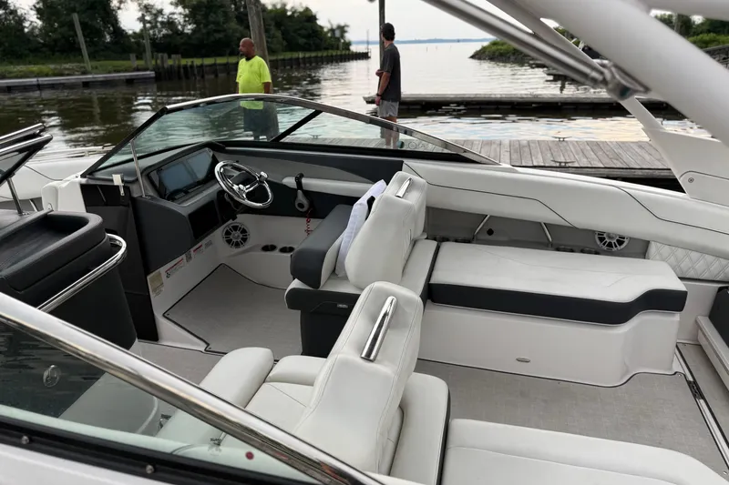 Slide: The Image of 2023 Regal LX4 boat interior with white seating, steering wheel, and dock view. - 11