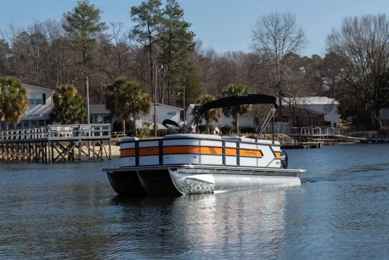 Slide: The Image of 2026 Bentley Pontoons 223 Bolt Tri-Toon on a serene lake with trees and houses. - 37
