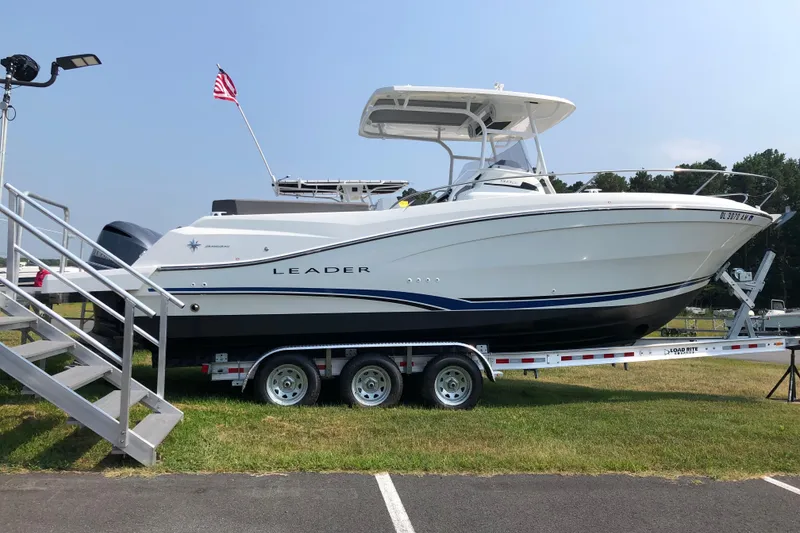 The Image of 2019 Jeanneau Leader 9.0 CC boat on trailer, displayed outdoors with American flag. - 1