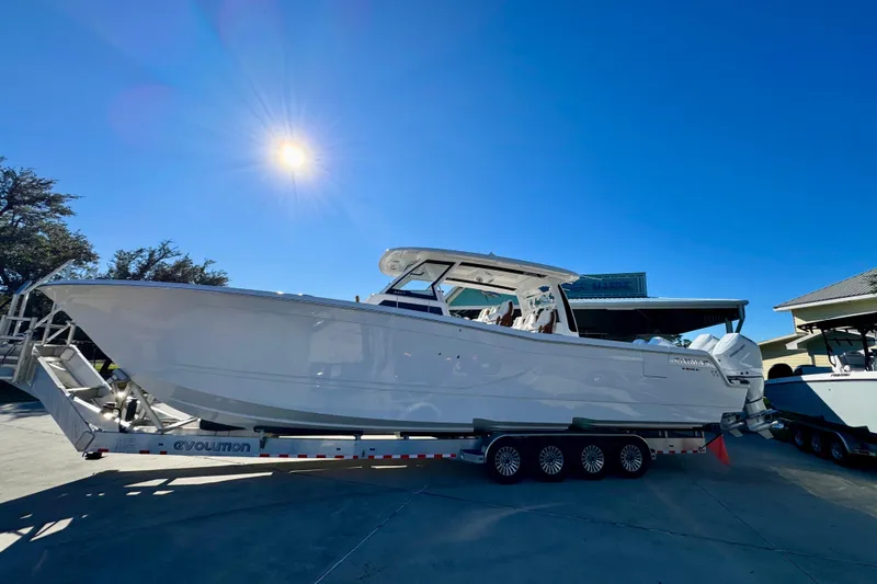 The Image of 2026 Caymas 44 CT boat on trailer under bright sunlit sky. - 1
