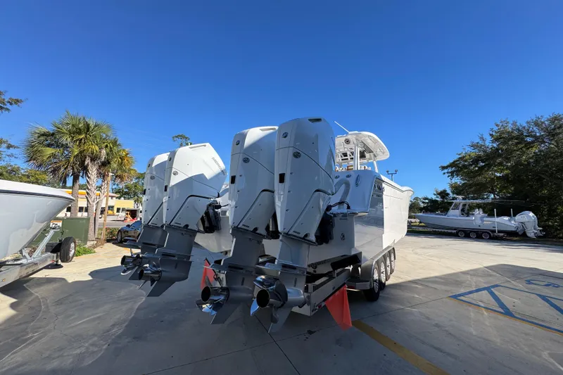 Slide: The Image of 2026 Caymas 44 CT boat with powerful outboard engines, parked outdoors under clear blue sky. - 11