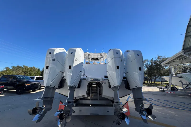 Slide: The Image of 2026 Caymas 44 CT boat with four powerful outboard engines, parked outdoors. - 12