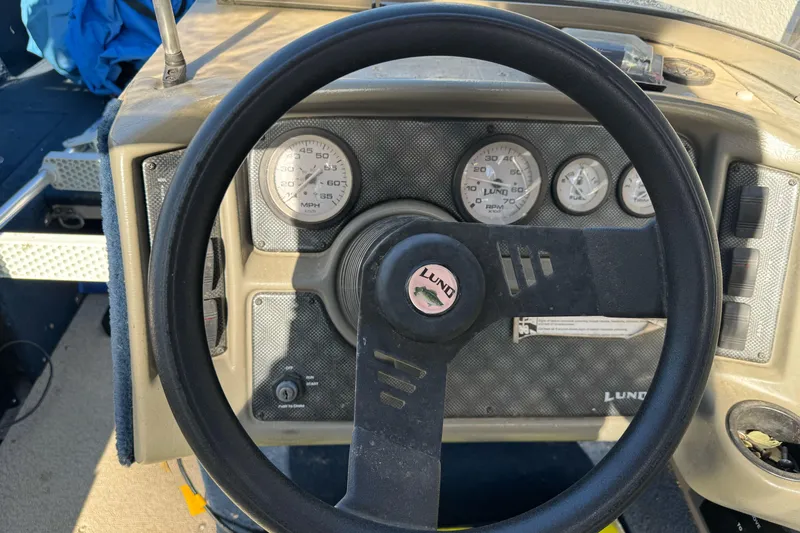 Slide: The Image of Dashboard of a 2001 Lund 1700 Pro Sport boat with steering wheel and gauges. - 13