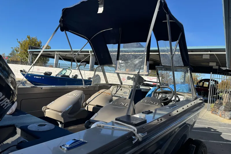 Slide: The Image of 2001 Lund 1700 Pro Sport boat with canopy, parked outdoors under clear sky. - 15