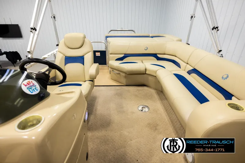 Slide: The Image of 2015 Lowe SS 210 pontoon boat interior with beige and blue seating, steering wheel, and logo. - 14