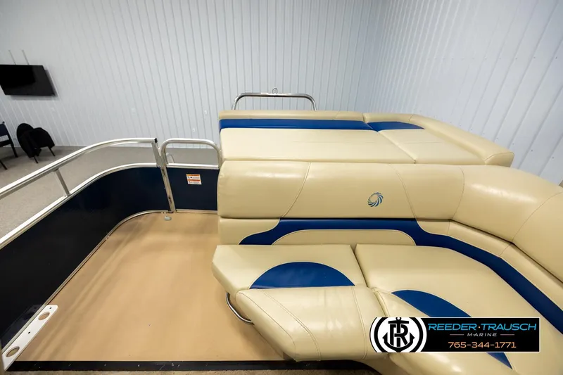Slide: The Image of 2015 Lowe SS 210 pontoon boat interior with beige and blue seating in showroom. - 15