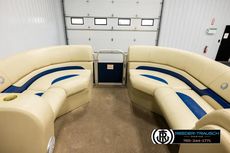 Slide: The Image of 2015 Lowe SS 210 pontoon boat interior with beige and blue seating in a garage. - 18