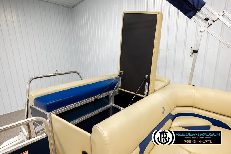 Slide: The Image of 2015 Lowe SS 210 pontoon boat interior with beige and blue seating in a showroom. - 23
