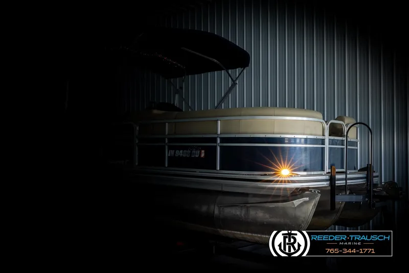 Slide: The Image of 2015 Lowe SS 210 pontoon boat in dimly lit storage, Reeder-Trausch Marine logo visible. - 4