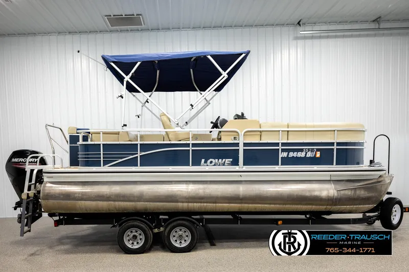 Slide: The Image of 2015 Lowe SS 210 pontoon boat with blue canopy on trailer in showroom. - 5
