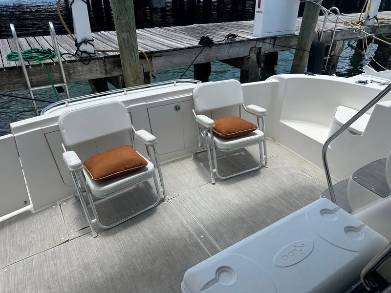 Slide: The Image of 2007 Meridian 411 Sedan yacht deck with two chairs and cushions, docked by wooden pier. - 12