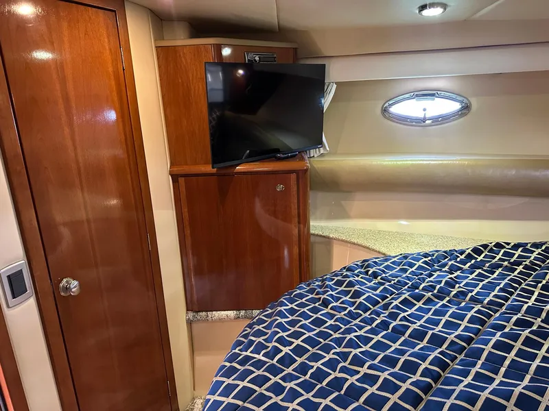 Slide: The Image of 2007 Meridian 411 Sedan cabin with TV, wooden cabinetry, and blue checkered bedding. - 20