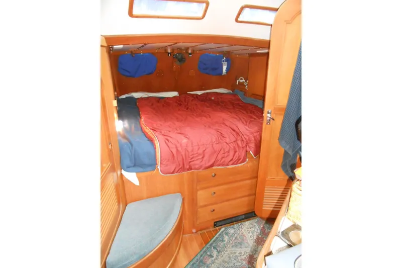 Slide: The Image of Cozy cabin interior of 1989 Norseman 447 sailboat with wooden furnishings and red bedding. - 9