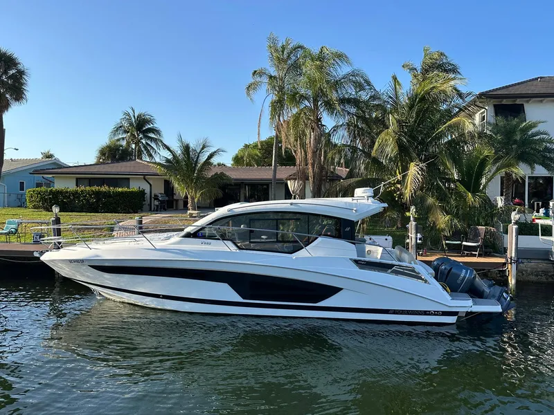 The Image of 2020 Four Winns Vista 355 Coupe docked by a waterfront home with palm trees. - 1