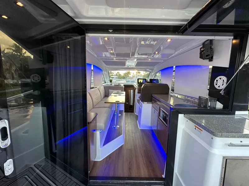 Slide: The Image of 2020 Four Winns Vista 355 Coupe interior with modern design, blue LED lighting, and wood flooring. - 23