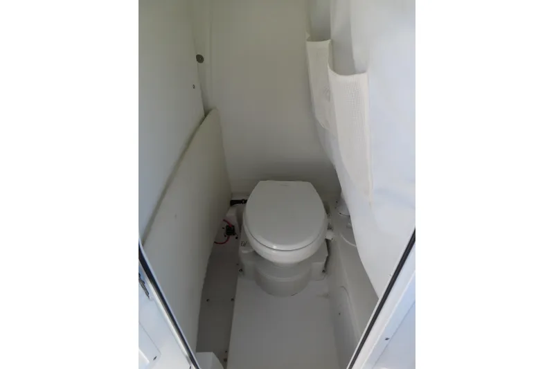 Slide: The Image of 2025 Sea Hunt Ultra 245 SE boat interior with compact marine toilet. - 19