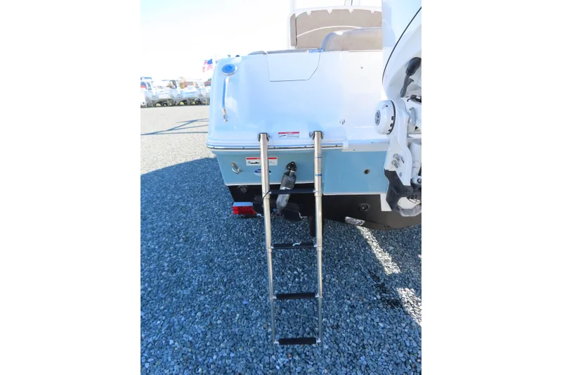 Slide: The Image of 2025 Sea Hunt Ultra 245 SE boat with rear ladder on gravel surface. - 6