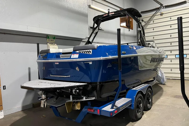 Slide: The Image of 2022 Moomba Mojo boat in a garage, blue exterior, on a trailer. - 2