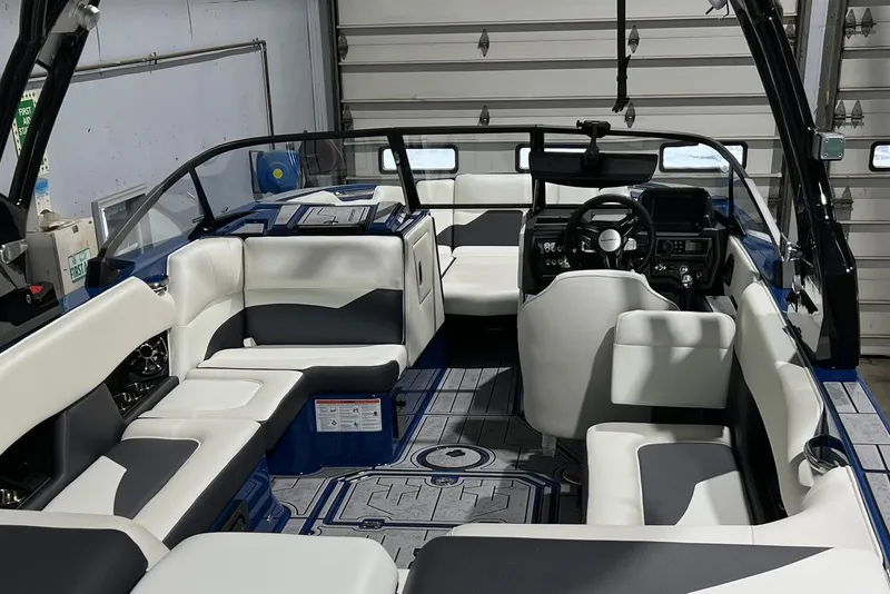 Slide: The Image of 2022 Moomba Mojo boat interior with sleek seating and modern dashboard in a garage setting. - 3
