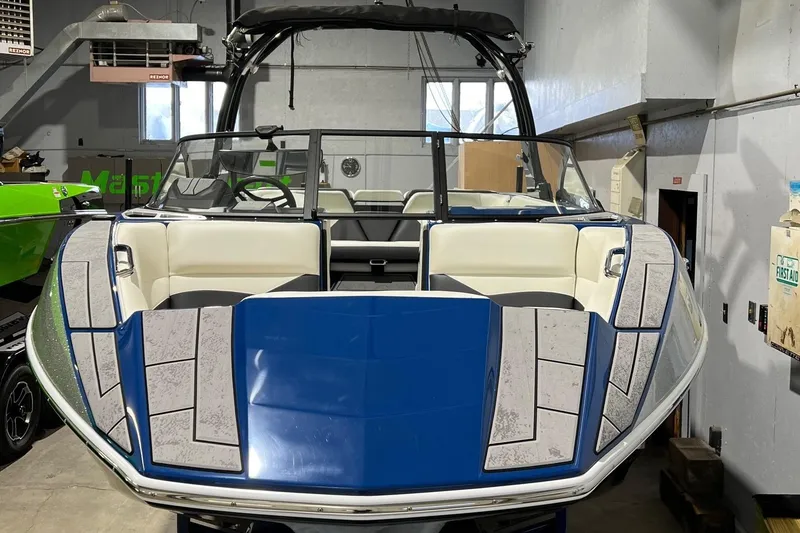 Slide: The Image of 2022 Moomba Mojo boat with blue and white interior in a garage setting. - 5