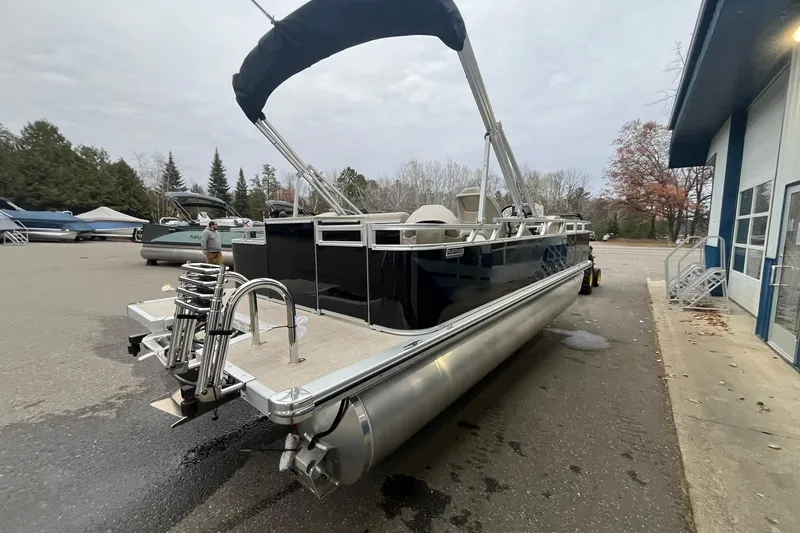 Slide: The Image of 2026 Avalon VTX Quad Fish pontoon boat with canopy, parked outdoors near a building. - 4