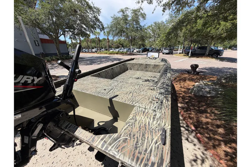 Slide: The Image of 2026 Tracker Grizzly 1648 Utility boat with camouflage design, parked outdoors. - 2