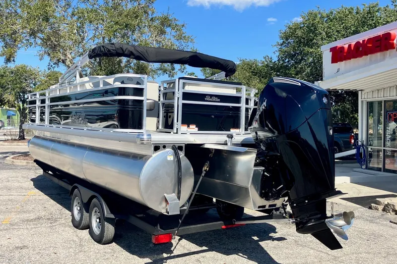 Slide: The Image of 2026 Sun Tracker Fishin' Barge 22 XP3 pontoon boat with Mercury outboard motor, parked outdoors. - 2