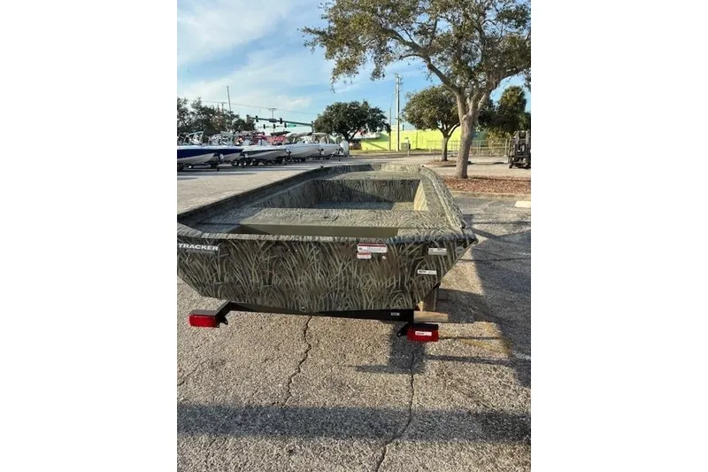 Slide: The Image of 2026 Tracker Grizzly 1754 Utility boat in a parking lot, featuring camouflage design. - 2