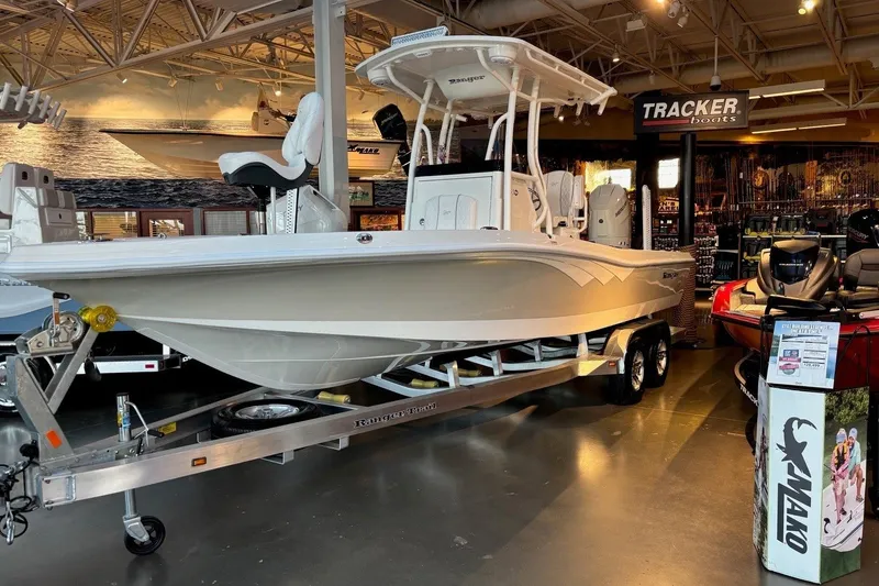 Slide: The Image of 2026 Ranger 2510 Bay boat displayed indoors on a trailer at a showroom. - 2