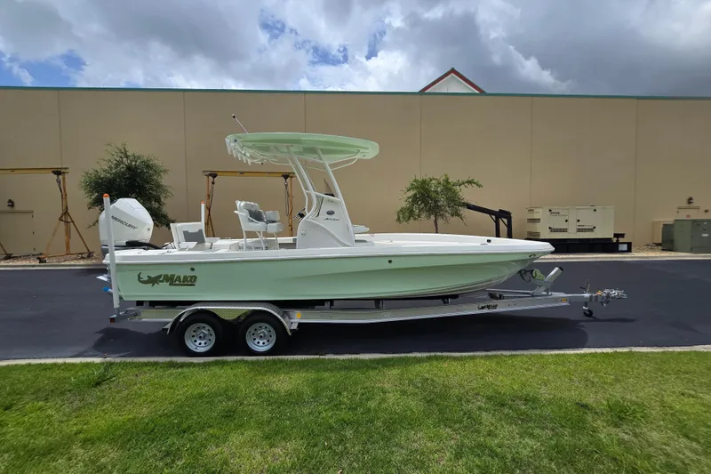 Slide: The Image of 2026 Mako 24 APEX boat on trailer, parked outdoors under cloudy sky. - 2