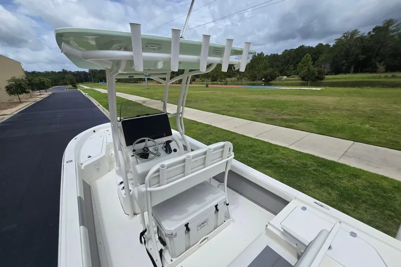 Slide: The Image of 2026 Mako 24 APEX boat with T-top and console, parked on a paved road. - 4