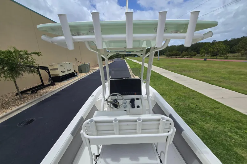 Slide: The Image of 2026 Mako 24 APEX boat with center console and rod holders, parked outdoors. - 5